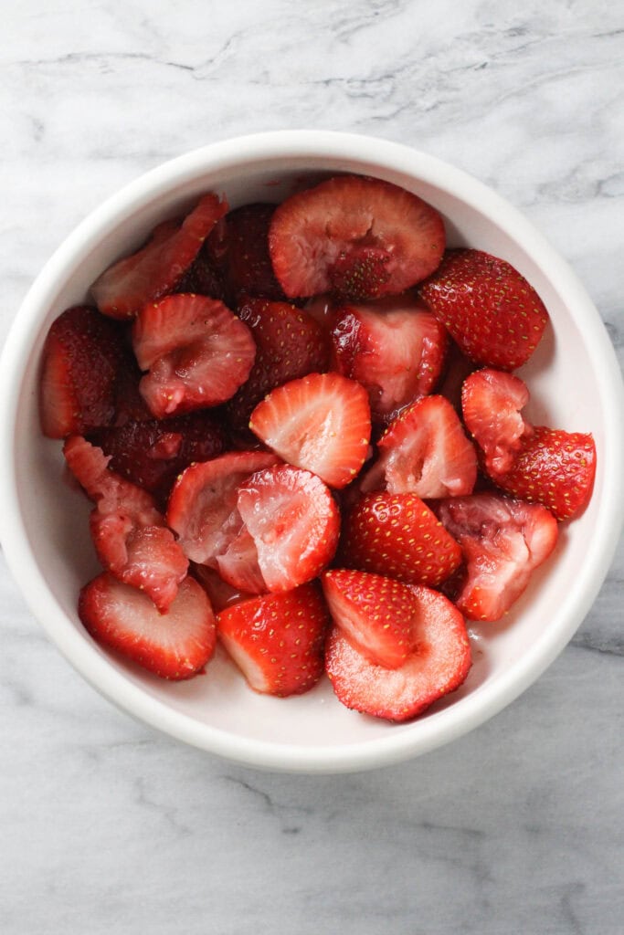 Lightly muddled strawberries in a bowl.