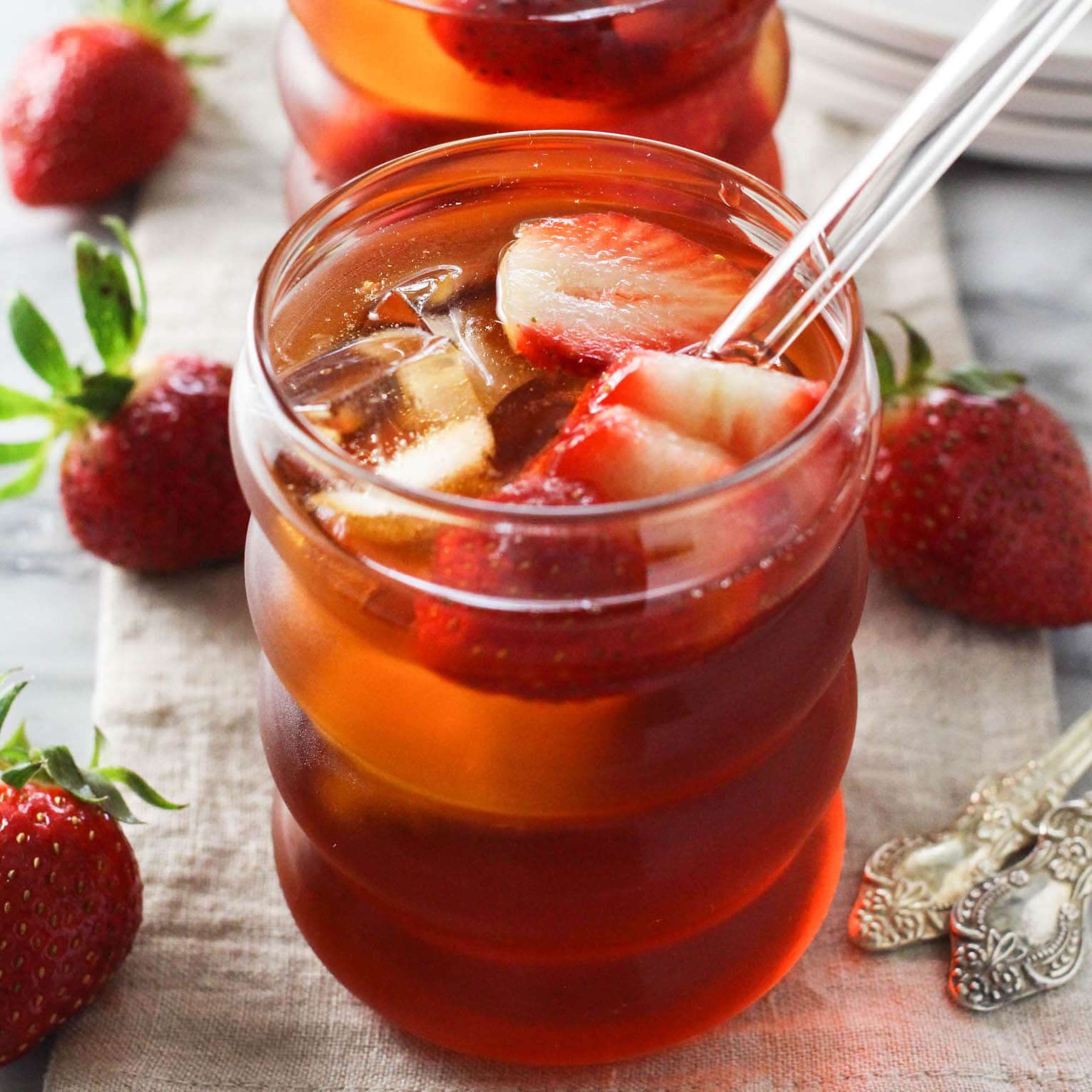Glass of strawberry rooibos iced tea served over ice with fresh strawberry slices.